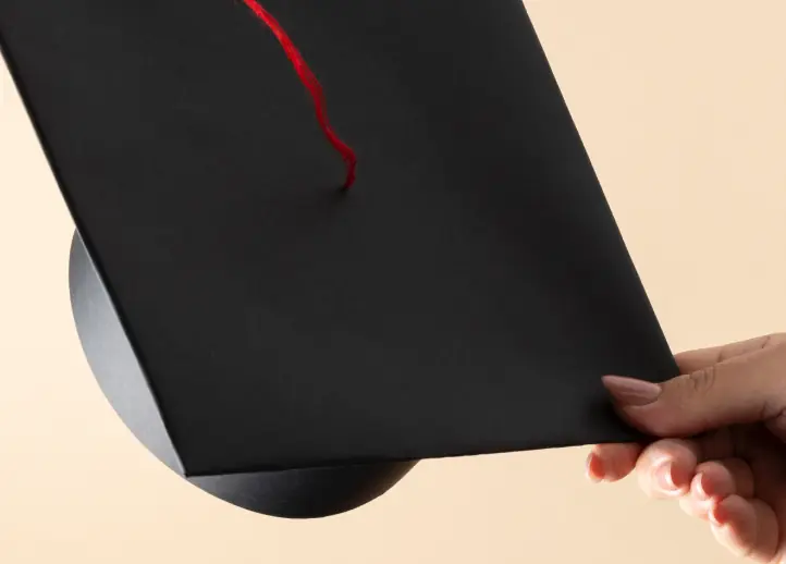 Estudante segurando o capelo no dia da formatura