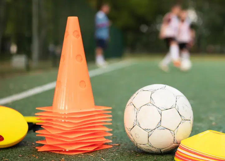 Cones e bola de futebol em um campo durante um treino
